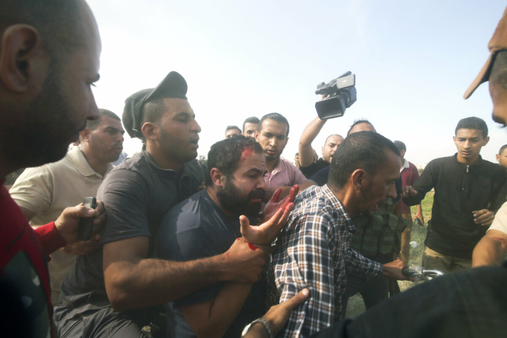 Những người Palestine chở một thường dân Israel bị bắt (giữa) từ Kibbutz Kfar Azza vào Dải Gaza hôm 07/10/2023. (Ảnh: AP Photo/Hatem Ali)